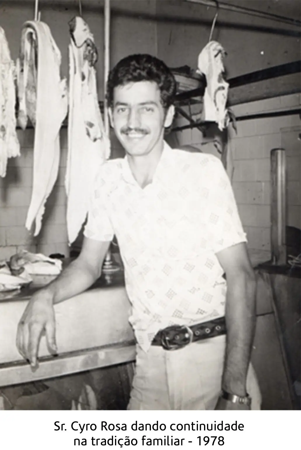 Fotografia histórica em preto e branco de Cyro Rosa no balcão de uma casa de carnes
